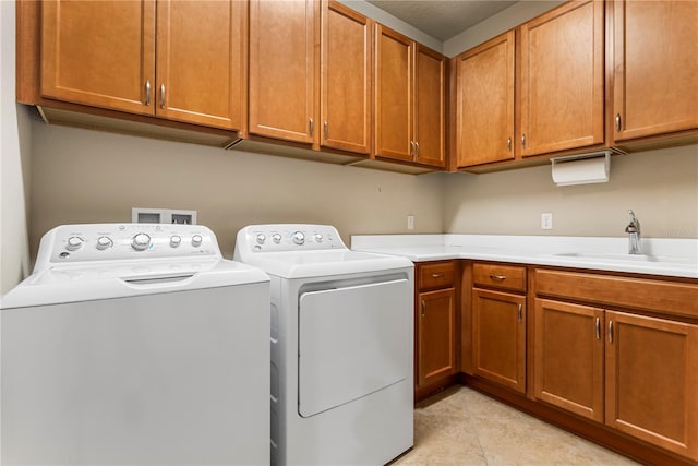 clothes washing area with washing machine and clothes dryer, cabinets, sink, and light tile floors