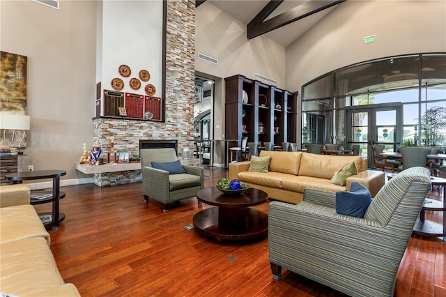 living room featuring dark wood-type flooring, high vaulted ceiling, a stone fireplace, a wall mounted AC, and french doors