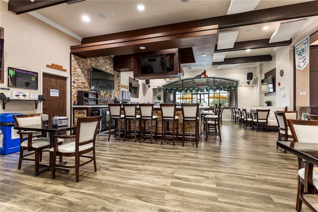 dining room featuring hardwood / wood-style floors, bar area, and beamed ceiling