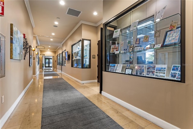 hallway featuring ornamental molding and light tile floors