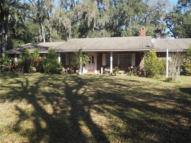 ranch-style house featuring brick siding, a chimney, and a front yard