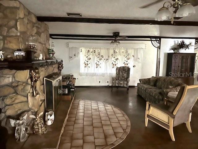 living area featuring a ceiling fan, a fireplace, and beamed ceiling