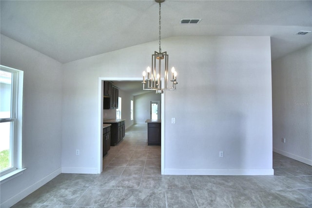 tiled empty room with a notable chandelier and vaulted ceiling