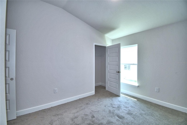 carpeted empty room with vaulted ceiling