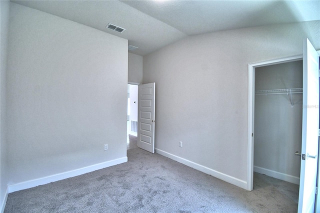 unfurnished bedroom with light carpet, a closet, and vaulted ceiling