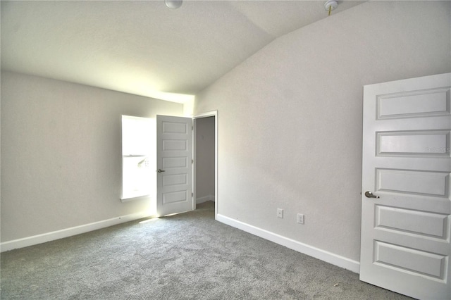 unfurnished bedroom with dark carpet and vaulted ceiling