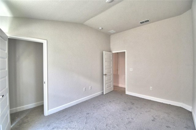 carpeted spare room with a textured ceiling and vaulted ceiling