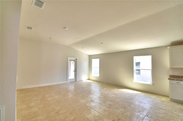 spare room with light tile flooring, a healthy amount of sunlight, and vaulted ceiling