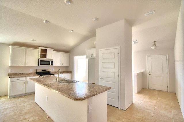 kitchen featuring an island with sink, sink, light tile floors, stove, and white cabinetry