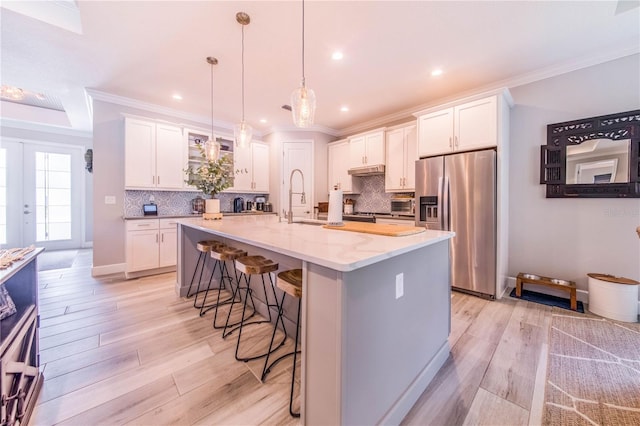 kitchen with light hardwood / wood-style floors, white cabinets, backsplash, and stainless steel fridge