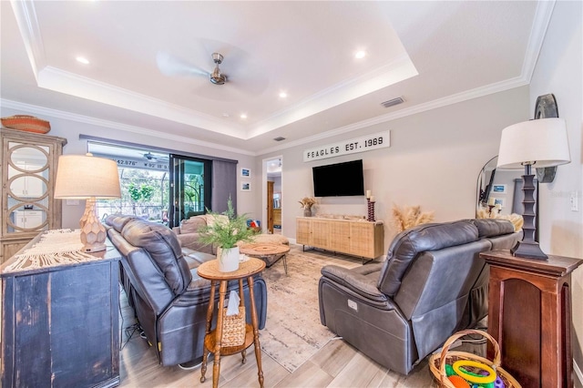 living room with a raised ceiling, light hardwood / wood-style flooring, ceiling fan, and ornamental molding