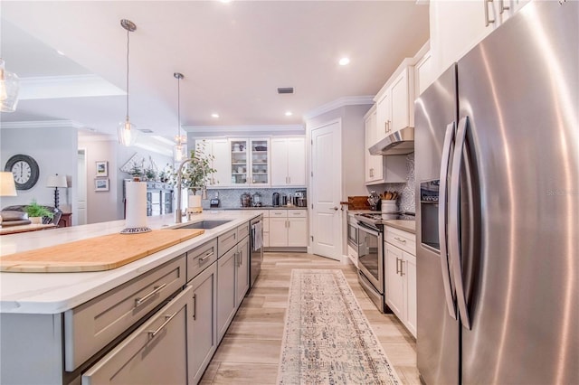 kitchen featuring an island with sink, stainless steel appliances, tasteful backsplash, decorative light fixtures, and white cabinetry