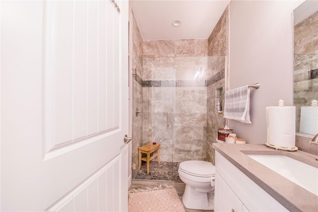 bathroom with toilet, tile flooring, vanity, and tiled shower