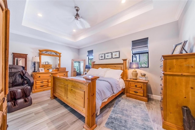 bedroom featuring crown molding, a raised ceiling, and light wood-type flooring