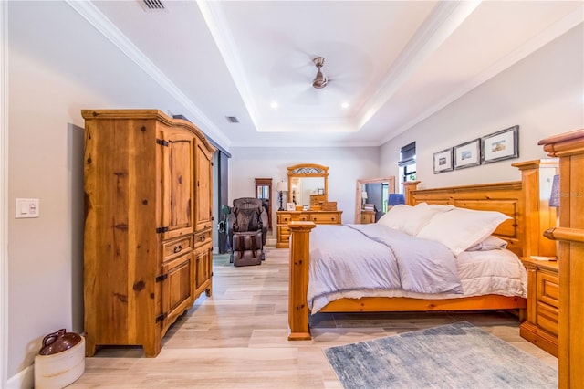 bedroom featuring a raised ceiling, crown molding, and light hardwood / wood-style flooring