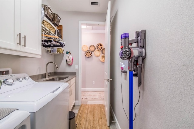 clothes washing area featuring cabinets, sink, light tile floors, and washer and clothes dryer