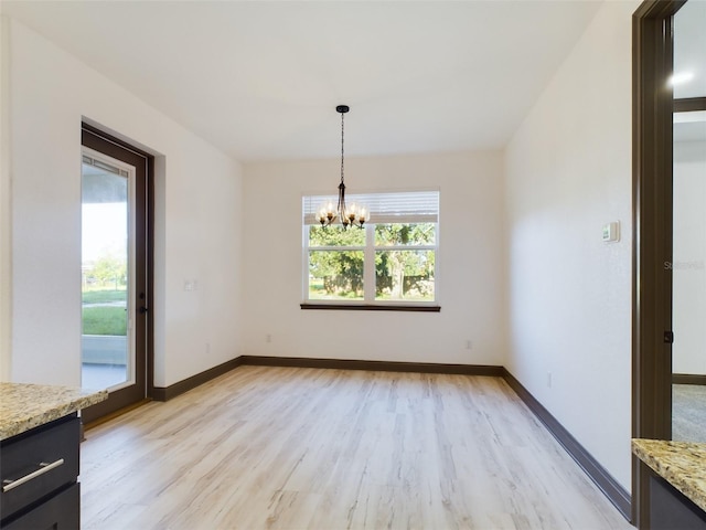 unfurnished dining area with a chandelier and light hardwood / wood-style floors