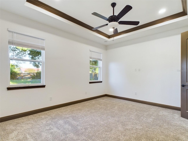 carpeted spare room with crown molding, ceiling fan, and a raised ceiling