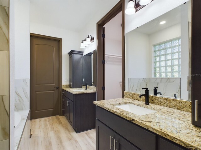 bathroom featuring vanity, wood-type flooring, and a tub