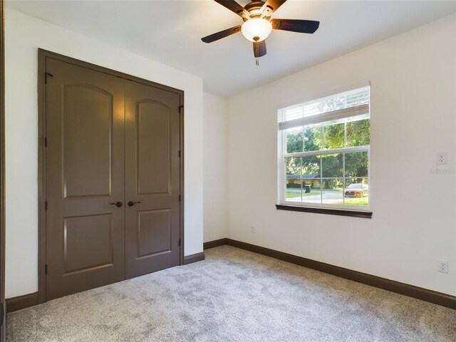 unfurnished bedroom with light colored carpet, ceiling fan, and a closet