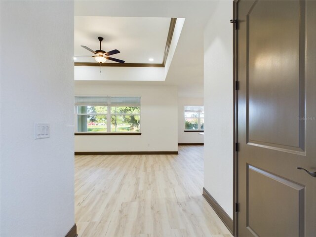 interior space featuring light wood-type flooring, a raised ceiling, and ceiling fan