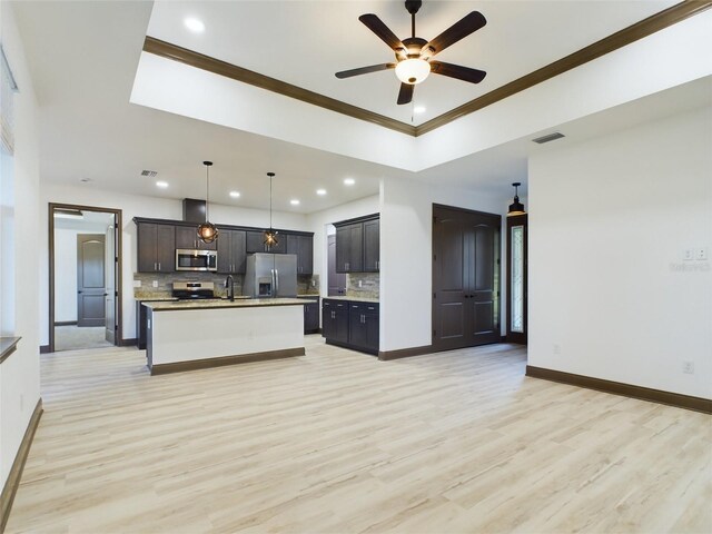 kitchen with tasteful backsplash, sink, ceiling fan, appliances with stainless steel finishes, and a center island with sink