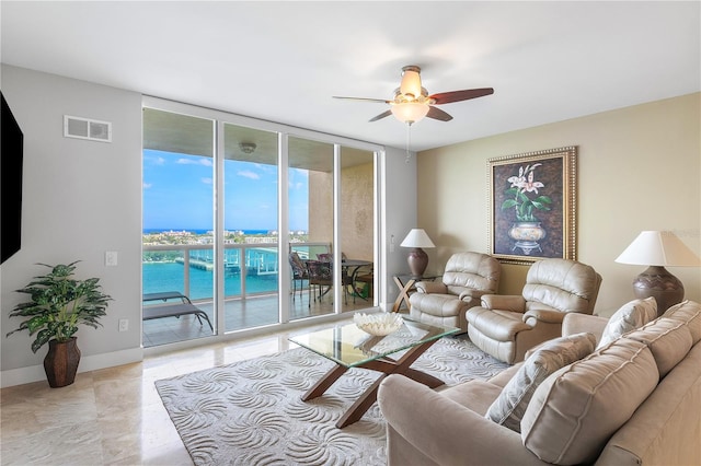 living room with floor to ceiling windows, a water view, ceiling fan, and light tile floors