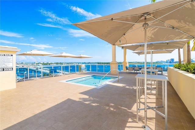 view of swimming pool featuring a water view, a hot tub, and a patio