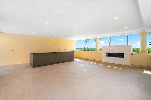 unfurnished living room with plenty of natural light, a textured ceiling, and light tile floors