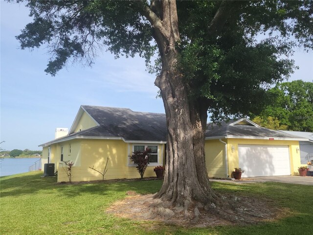 view of property exterior featuring cooling unit, a garage, a lawn, and a water view