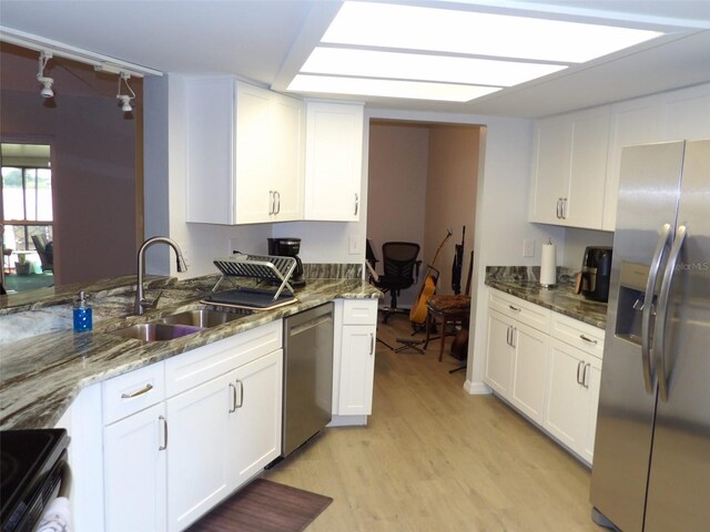 kitchen with white cabinetry, appliances with stainless steel finishes, sink, and dark stone countertops