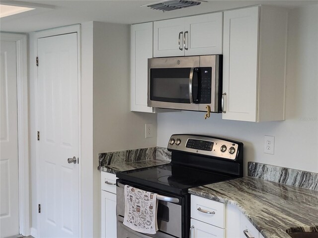 kitchen featuring stainless steel appliances, white cabinetry, and light stone countertops