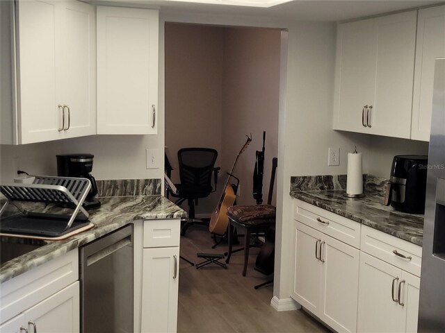 kitchen with dark stone countertops, light wood-type flooring, and white cabinets