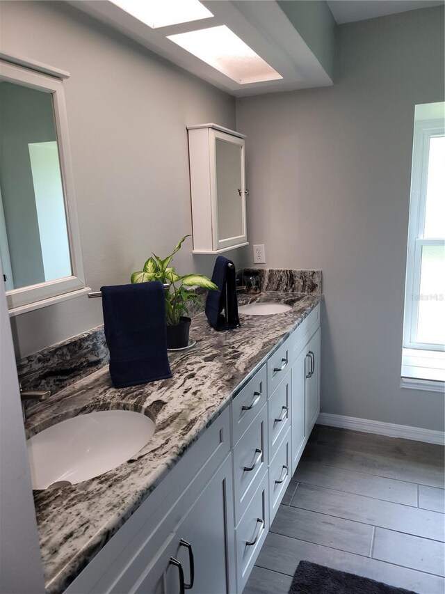 bathroom featuring vanity, a skylight, and wood-type flooring