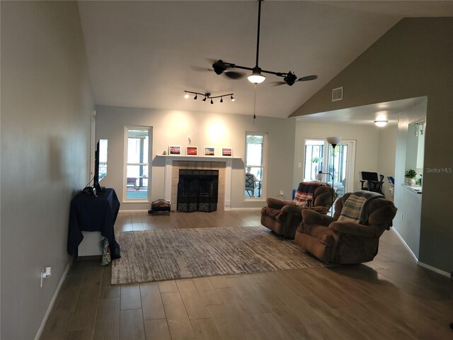 living room with ceiling fan, wood-type flooring, and a tile fireplace