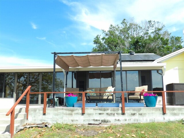 rear view of house featuring a sunroom, a patio, and solar panels