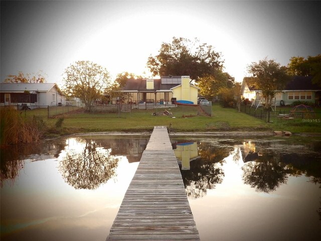 view of dock with a yard and a water view