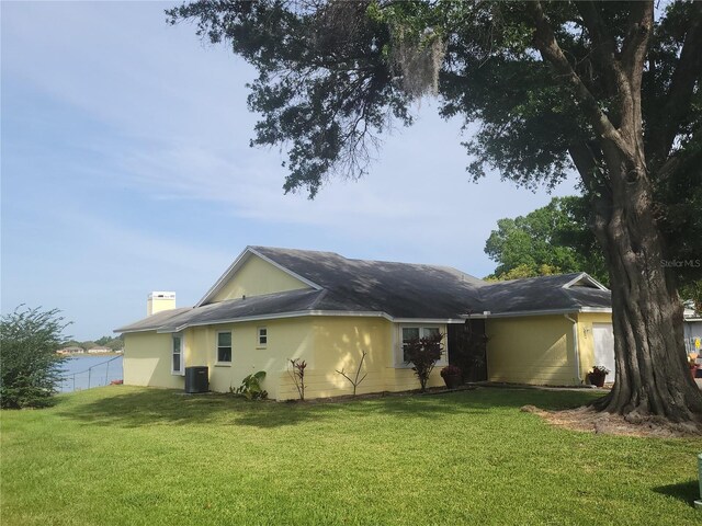 rear view of house featuring a yard, central air condition unit, and a water view