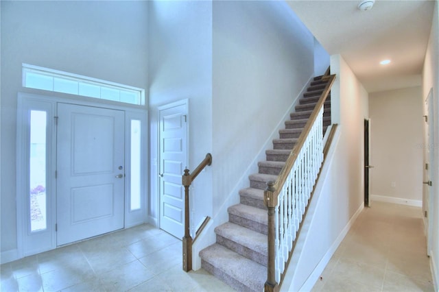 entryway with a towering ceiling and light tile floors