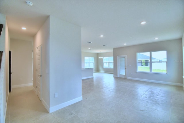 spare room featuring a notable chandelier and light tile floors