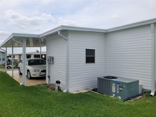 view of side of home with a lawn, central AC unit, and a carport