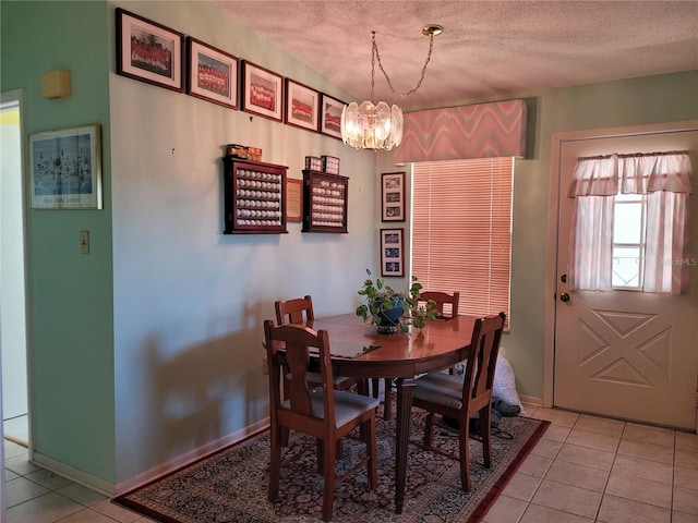 tiled dining space with a textured ceiling and a chandelier