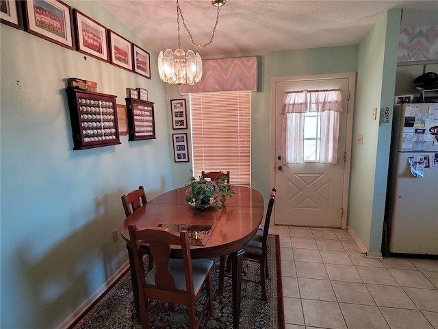 tiled dining space featuring a notable chandelier and a textured ceiling