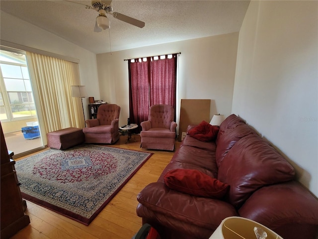 living room featuring a textured ceiling, vaulted ceiling, ceiling fan, and light wood-type flooring