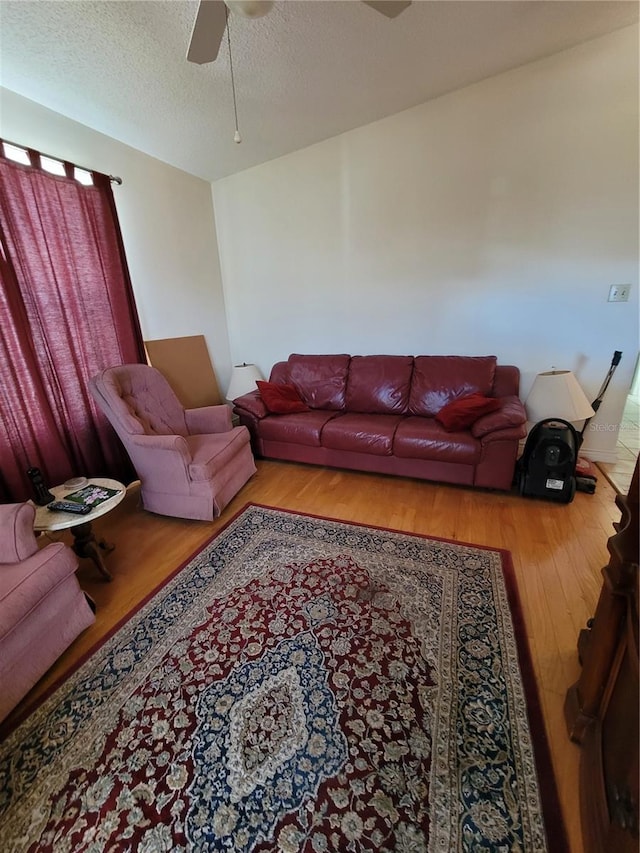 living room with ceiling fan, light hardwood / wood-style flooring, and a textured ceiling