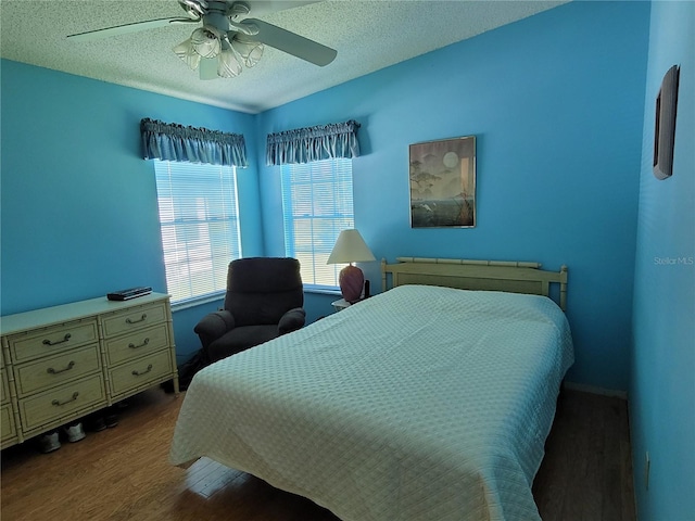 bedroom featuring dark hardwood / wood-style flooring, ceiling fan, and a textured ceiling