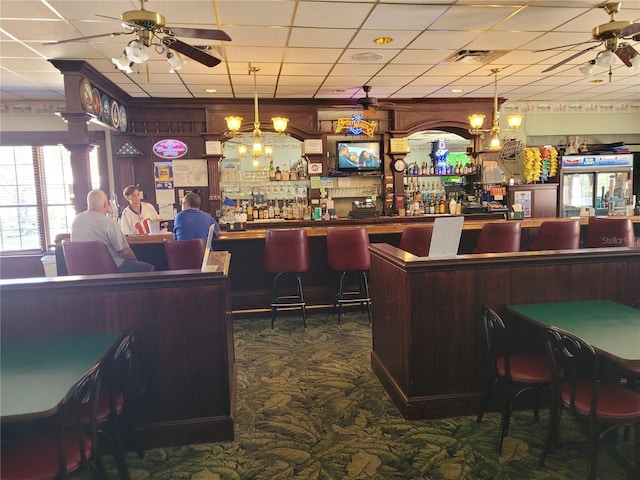 bar with dark carpet, dark brown cabinets, ceiling fan, and a drop ceiling