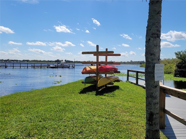 view of dock featuring a lawn and a water view