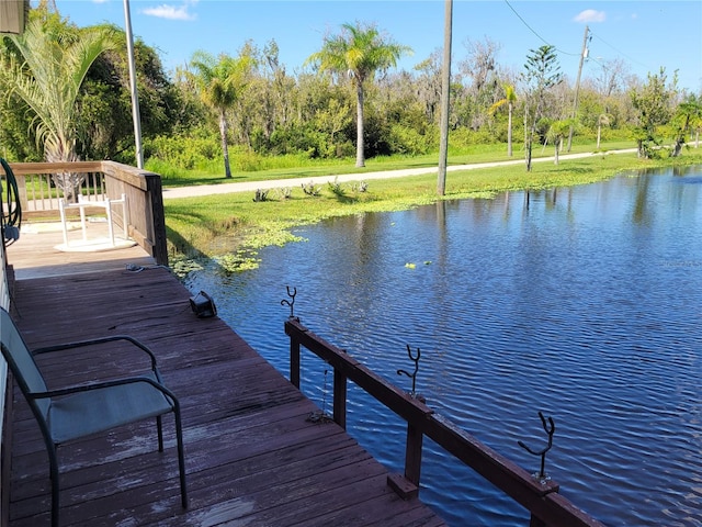 view of dock featuring a lawn and a water view