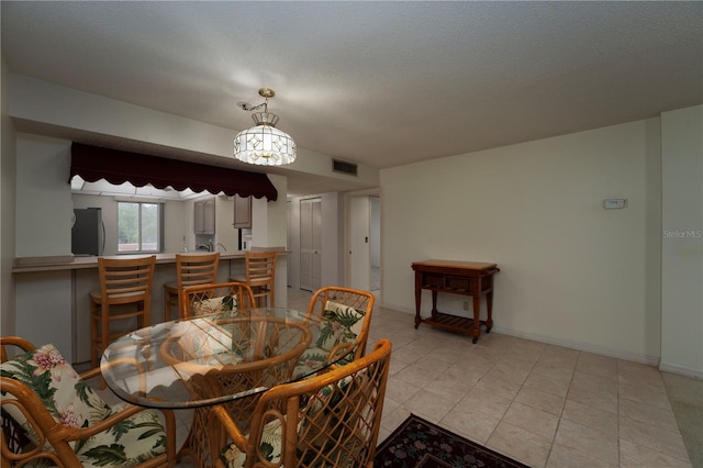 dining room featuring a textured ceiling and light tile floors